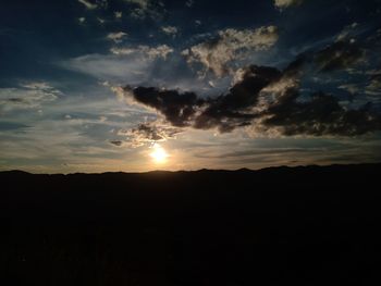 Silhouette landscape against dramatic sky during sunset