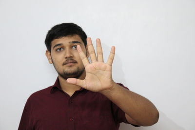 Portrait of young man standing against white background