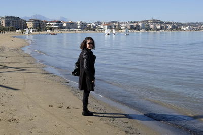 Full length of woman standing at beach against clear sky