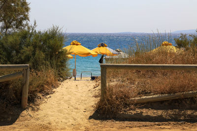Rear view of yellow umbrella on beach against clear sky