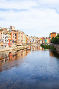 Houses by river in city against sky