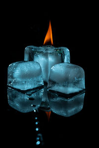 Close-up of burning candle against black background