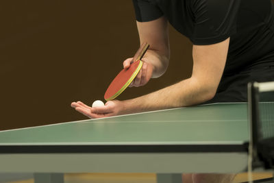 Midsection of man serving while playing table tennis