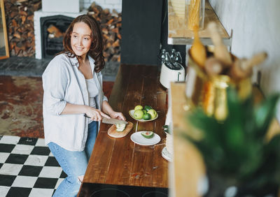 Young woman holding food while standing at restaurant table