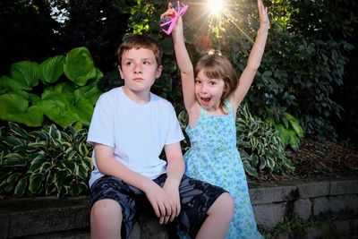 Portrait of girl with brother against plants