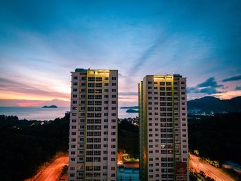 Modern buildings against sky at sunset