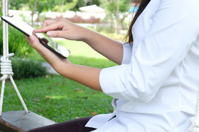 Midsection of woman using mobile phone in grass