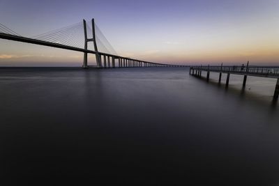 Bridge over sea against sky during sunset