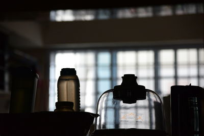 Glass container and bottles on table at home
