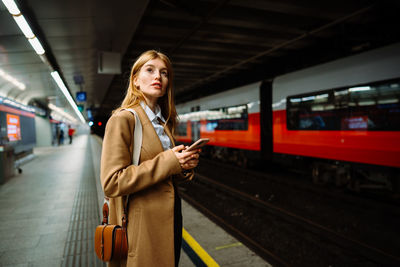 Beautiful attractive young woman standing on station platform in night time