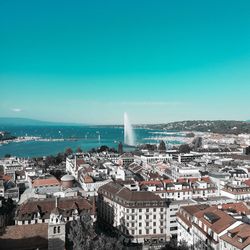 High angle view of buildings by sea against blue sky