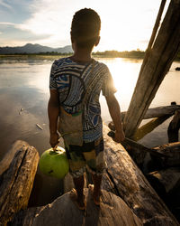 Rear view of boy standing by sea against sky