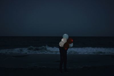 Man standing with balloons on beach