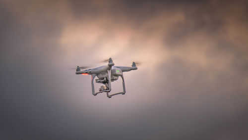 Low angle view of drone flying against sky
