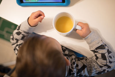 Midsection of man holding coffee cup on table at home