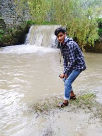 Full length of young man standing by stream