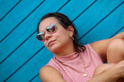 Portrait of young woman wearing sunglasses against wooden background 