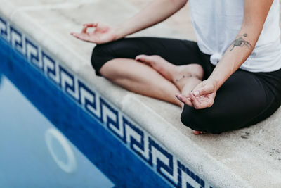 Low section of woman exercising by swimming pool