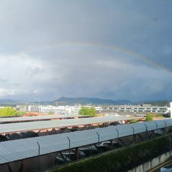 Rainbow over buildings in city against sky