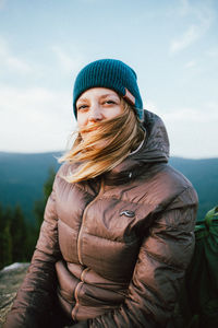 Portrait of young woman in hat against sky during winter