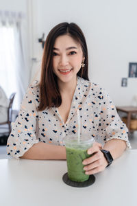 Portrait of smiling young woman sitting at home