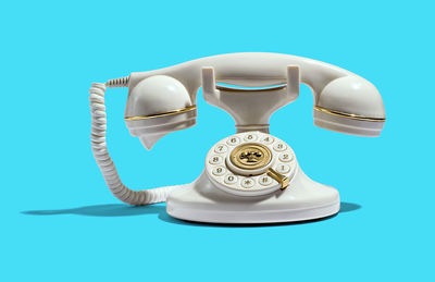 Close-up of telephone on table against blue background