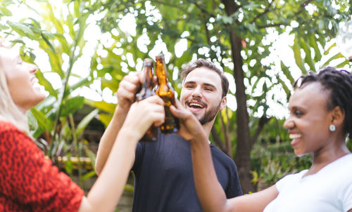 Happy friends toasting beer bottles