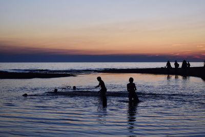 Silhouette people at beach during sunset