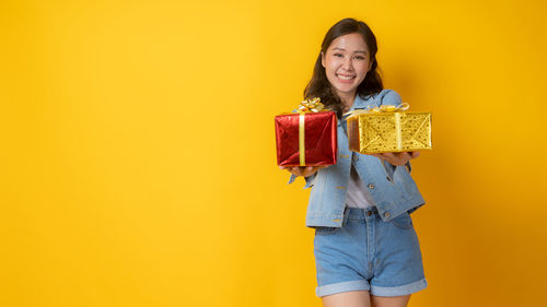 Portrait of a smiling young woman against yellow background