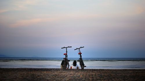 Rear view of women sitting by bicycle on promenade