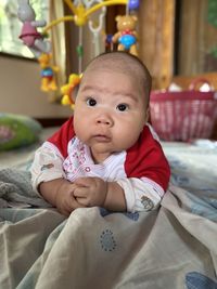 Portrait of cute baby girl on bed at home