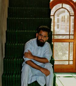 Portrait of young man sitting against window