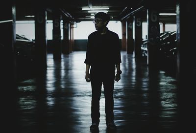 Full length of man looking away while standing in parking lot