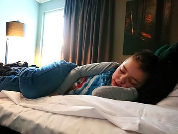 Boy sleeping on bed at home