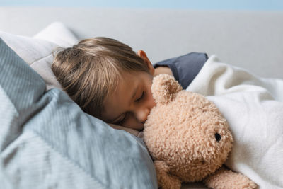 Portrait of cute baby boy with teddy bear on bed at home