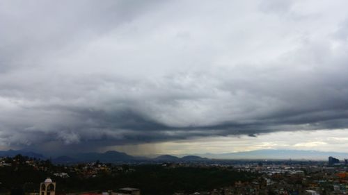 View of cityscape against cloudy sky