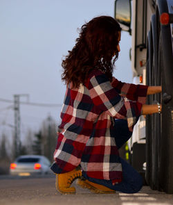 Side view of young woman holding railing on road