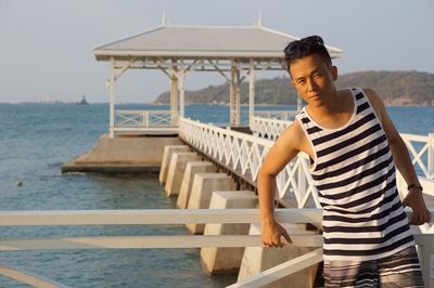 Portrait of man standing on railing on pier