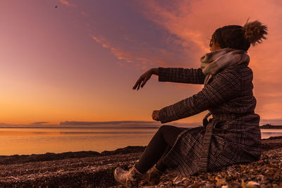 Man looking at sea against sky during sunset