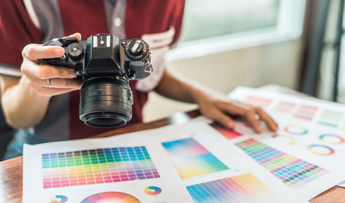 Midsection of woman photographing color swatch on table