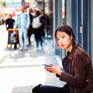 Young woman using mobile phone in city