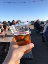 Cropped image of hand holding wine glass against clear sky