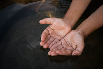 Cropped hands in lake during drought