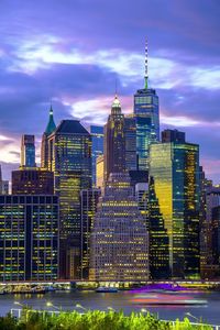 Illuminated buildings in city against cloudy sky