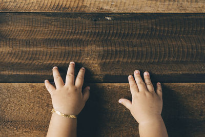 Cropped hands of baby girl on wooden table