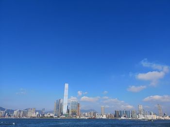 Sea by buildings against blue sky