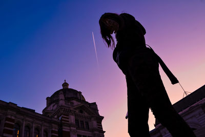 Low angle view of woman standing against clear sky during sunset