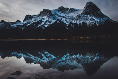 Scenic view of lake by snowcapped mountains against sky