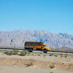 Train by road against clear blue sky