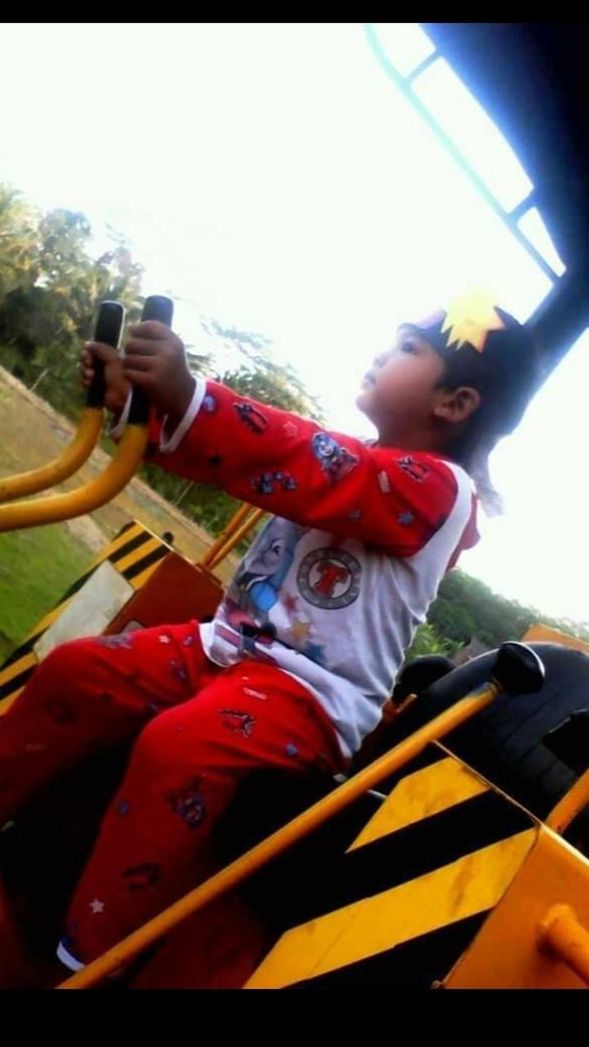 REAR VIEW OF BOY RIDING MOTORCYCLE ON PLAYGROUND